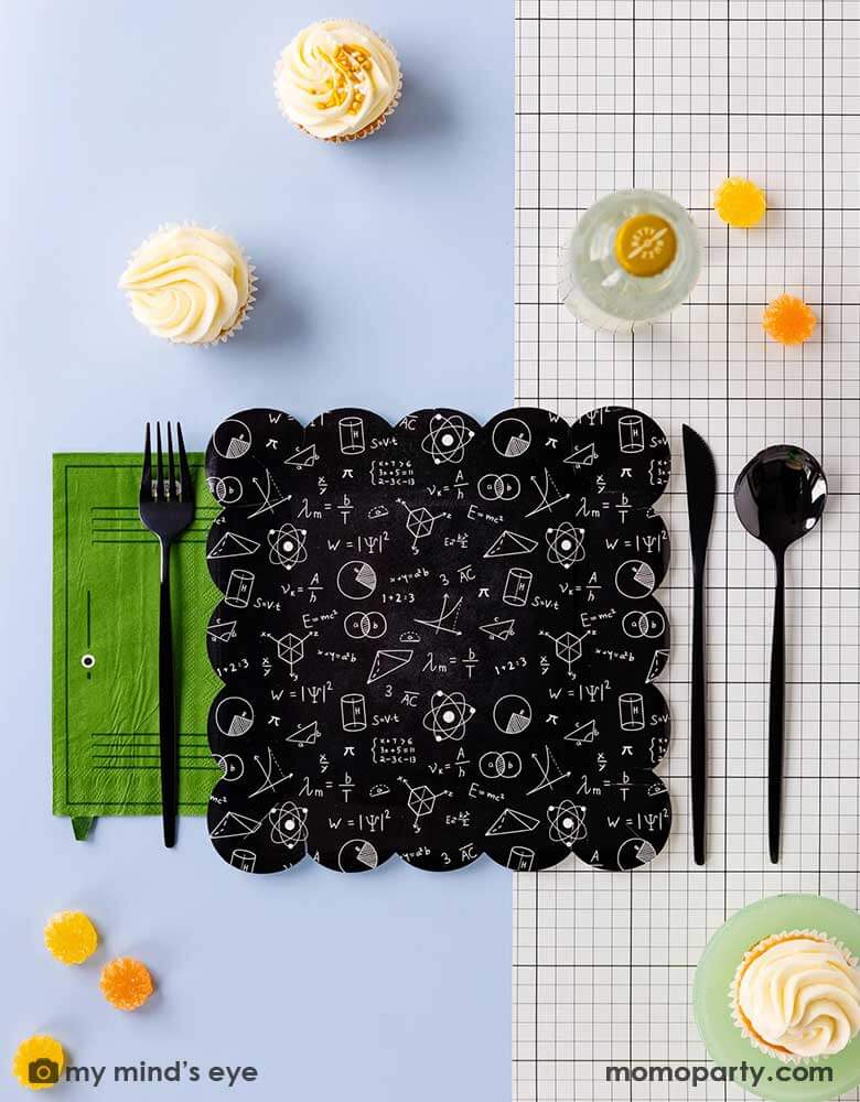 A modern back to school party placeset featuring Momo Party's school themed party supplies including the black equation plate, the green school locker shaped napkin, the back to school black and white grid table runner and some some black silverware, with some cupcakes and candies around this makes a simple and modern tablescape for a back to school or first day of school celebration.