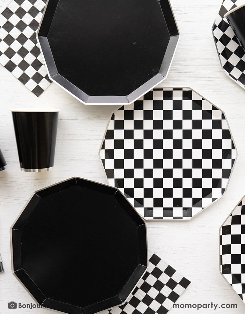 A table full of Momo Party's black themed party supplies including the 10.75" Black Noir Premium Dinner Plates, the checkered plates and napkins and the Black Noir Premium Party cups by Bonjour Fete. These elegant tablewares are chic and stylish. They are the perfect basic additions to your dinnerware collection.