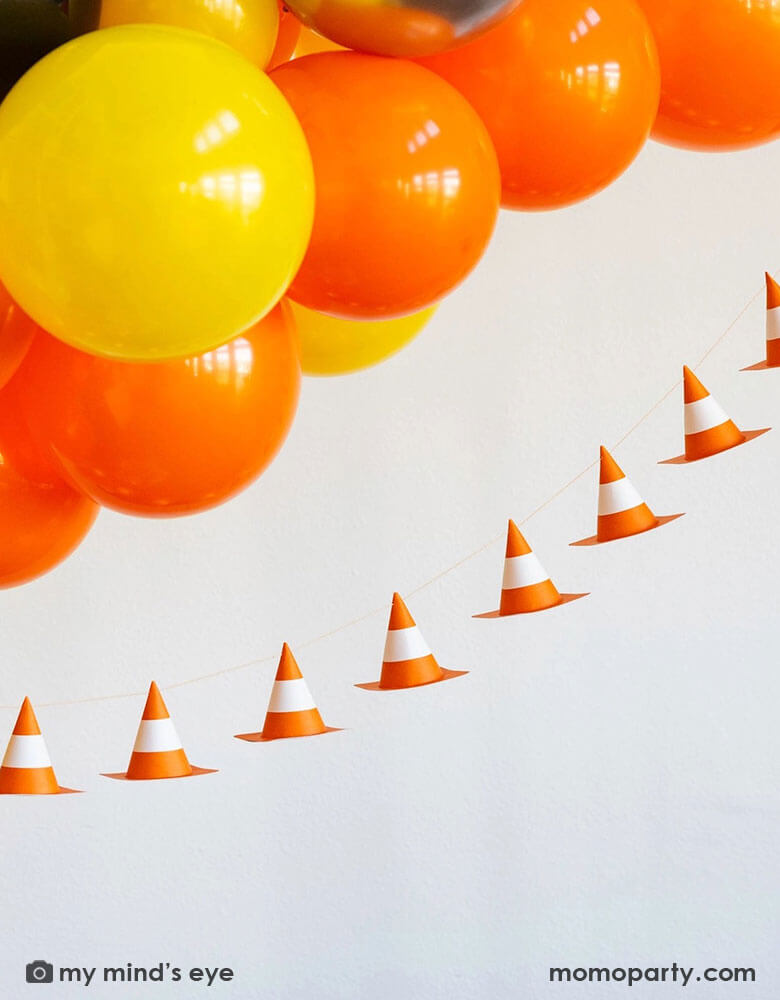 A kid's construction themed birthday party decoration featuring a balloon garland in classic construction colors of orange yellow and black,  adorned with Momo Party's 6f 3D construction cone paper banner, making this a perfect inspo for boy's construction themed birthday party decoration.