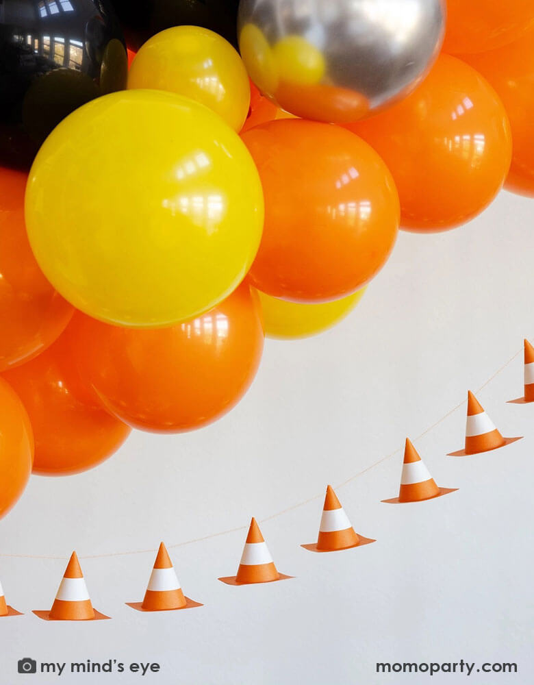 A kid's construction themed birthday party decoration featuring a balloon garland in classic construction colors of orange yellow, sliver and black,  adorned with Momo Party's 6f 3D construction cone paper banner, making this a perfect inspo for boy's construction themed birthday party decoration.