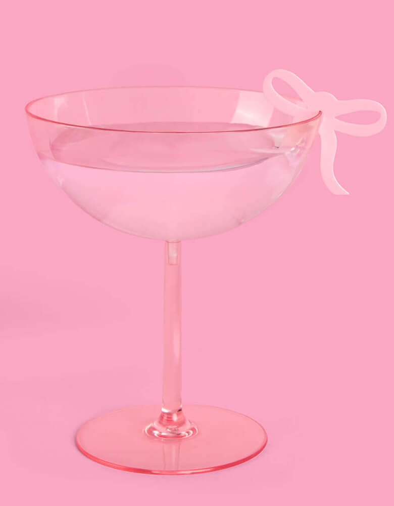 A pink cocktail glass adorned with Momo Party's coquette bow drink marker by Xo, Fetti. Whether it's a bday, bridal shower, or a bachelorette party, celebrate in bow bliss with this super cute drink marker.