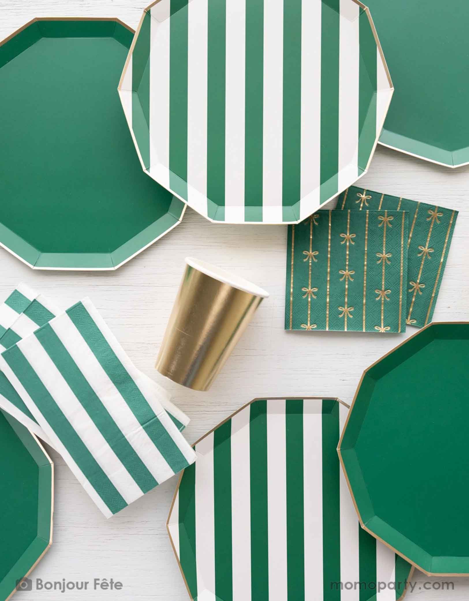 A overhead shot of a party table featuring Momo Party's emerald green and cabana stripe tableware including plates and napkins. With the gold foil bow small napkins and the gold party cup, it brings an elegant touch to your gathering, whether it's a Christmas dinner, a jungle or dinosaur themed birthday party, a football or Super Bowl celebration.