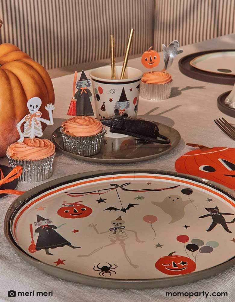 A vintage inspired Halloween table setting featuring Momo Party's This is Halloween! dinner plates, pumpkin shaped napkins, party cups, cupcakes topped with This is Halloween cupcake toppers. On the table there's a honeycomb mouse decoration making this a eerie yet playful tablescape. 