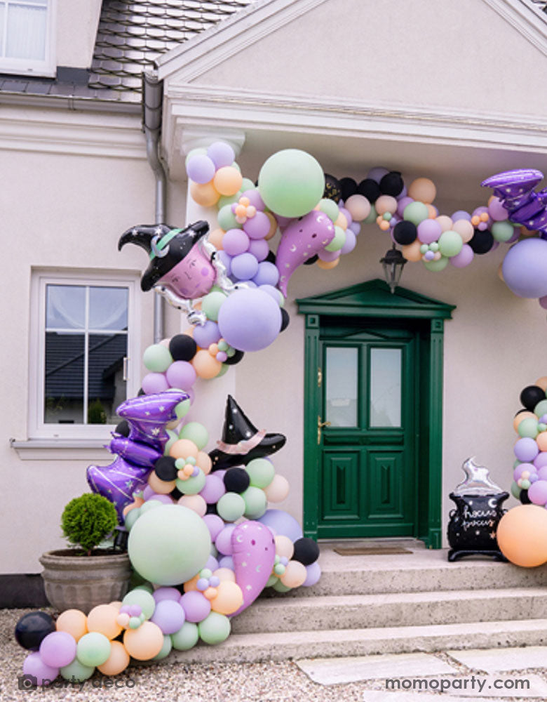 A witch inspired balloon installation at the entry door featuring Momo Party's Halloween witch themed foil balloons including the witch hat shaped foil balloon, the witch shaped foil balloon, the lilac ghost shaped balloons and the purple bat shaped foil balloons oon a pastel colored balloon garland, making this a spooky cute Halloween decoration in the not-so-spooky season!