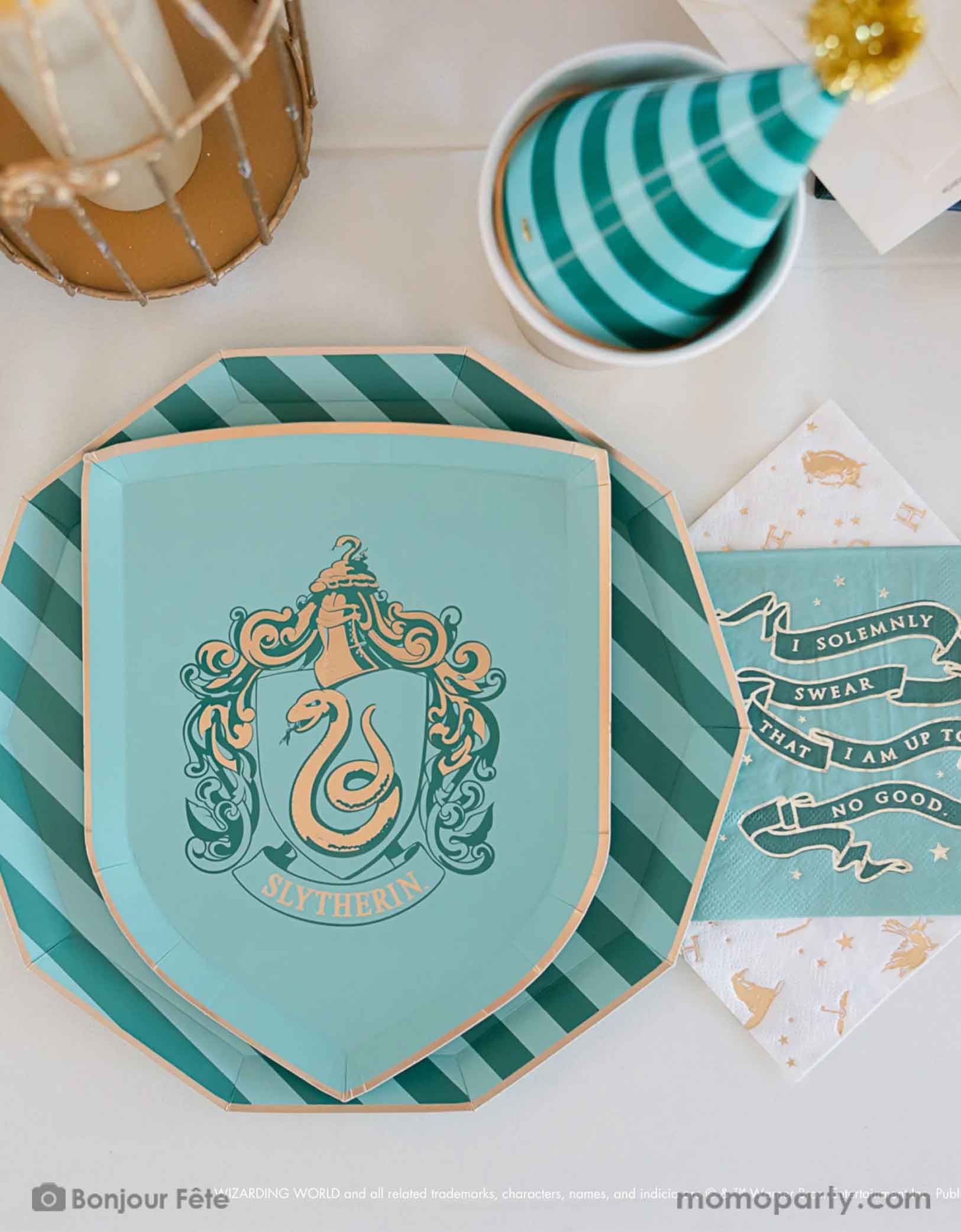 A beautiful and modern Harry Potter themed party tablescape features Momo Party's Harry Potter house pride shield-shaped 7" side plate with Slytherin logo and color paired with 10.25 green striped dinner plate. Next to the plates are Harry Potter motif large napkins in gold foil and Slytherin green small napkins. On the table there are some letters from Hogwarts, a bird cage for an owl and a green striped party hat  - making this a great inspo for a modern Harry Potter themed birthday party celebration.