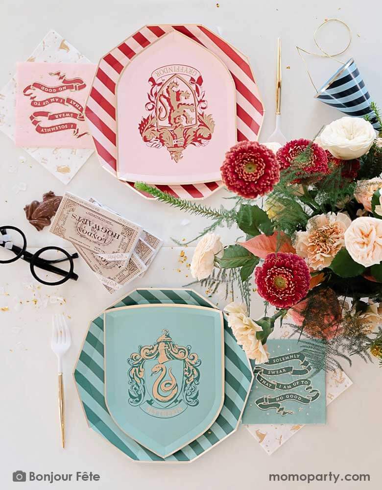 A beautiful and elegant Harry Potter themed party tablescape features Momo Party's Harry Potter house pride shield-shaped 7" side plates with Slytherin and Gryffindor logos and colors paired with 10.25 striped dinner plates. Next to the plates are Harry Potter motif large napkins in gold foil and matching small napkins from Momo Party. On the table there's a pair a Harry Potter's glasses, a Jelly Belly Chocolate Frog, tickets to Hogwarts and a beautiful flower arrangement. A magical party for kids!