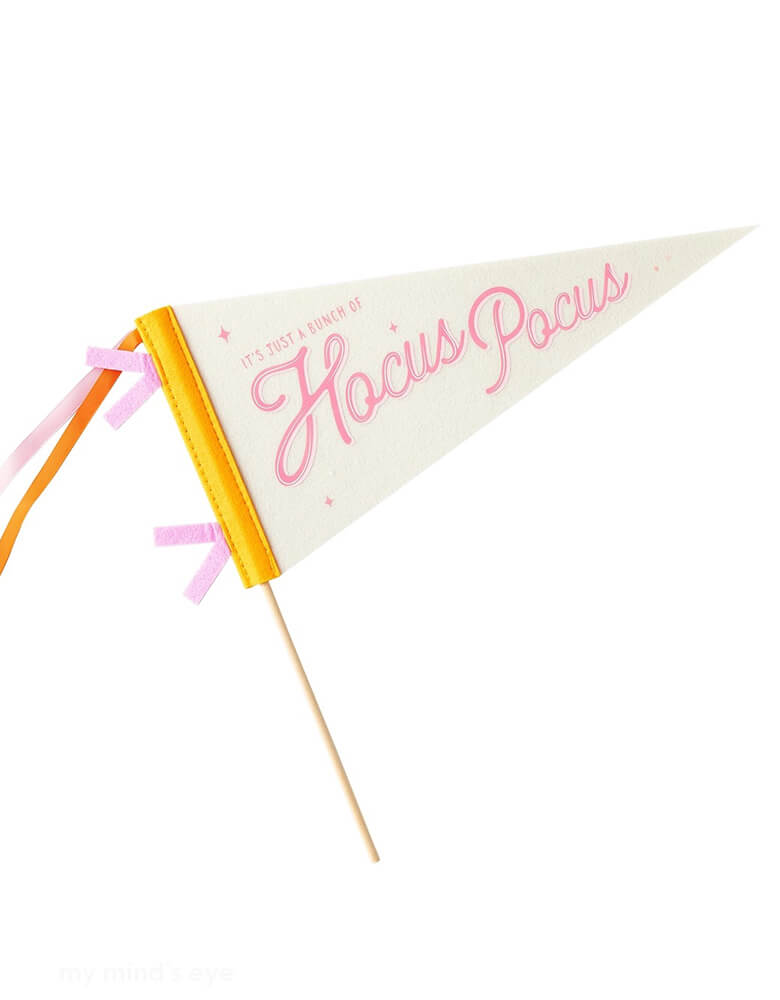 Momo Party's Hocus Pocus Felt Pennant by My Mind's Eye. Comes in orange and pink design and has "It's just a bunch of Hocus Pocus" on it,  this versatile pennant is perfect for Halloween parties, adding a touch of fun and whimsy to your decor. This felt pennant banner is a must-have for your next magical Halloween gathering!