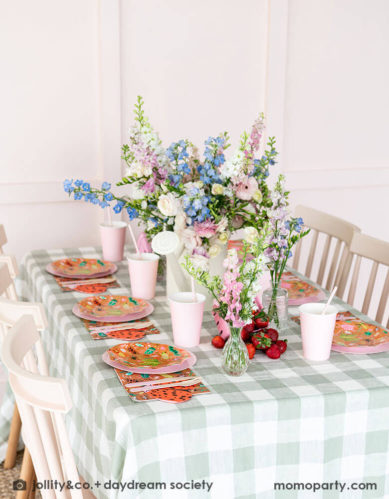 A cute kid's bug insect themed party table set up featuring Momo Party's backyard bug patterned plates, napkins paired with pink party cups and plates. With an olive green gingham tablecloth under and a beautiful flower bouquet, this makes a perfect inspiration for a modern take of a kid's bug themed celebration.