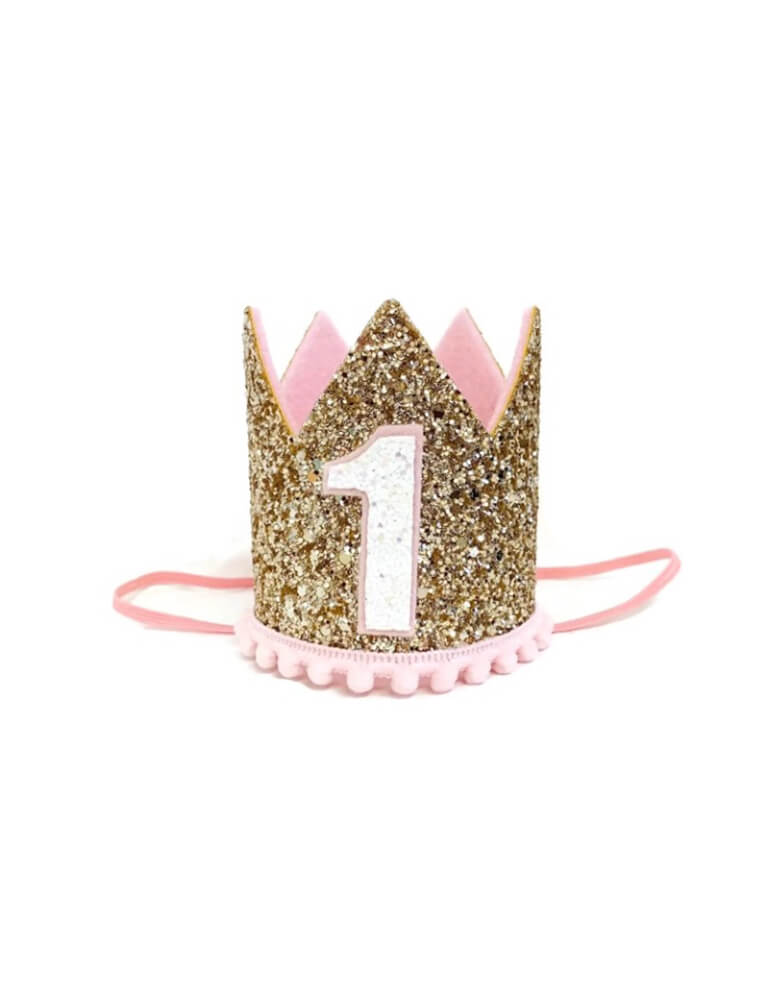 Momo Party's 3" pink and gold glittered first birthday party hat by Little Blue Olive. This adorable birthday crow with gold &amp; pale pink is perfect for your one year old baby girl! It's great for your little girl's first birthday party or a milestone photoshoot! This crown is hand-made of sturdy fabric, and is attached to a skinny elastic headband which is designed to be worn around the back of the head - like a headband.