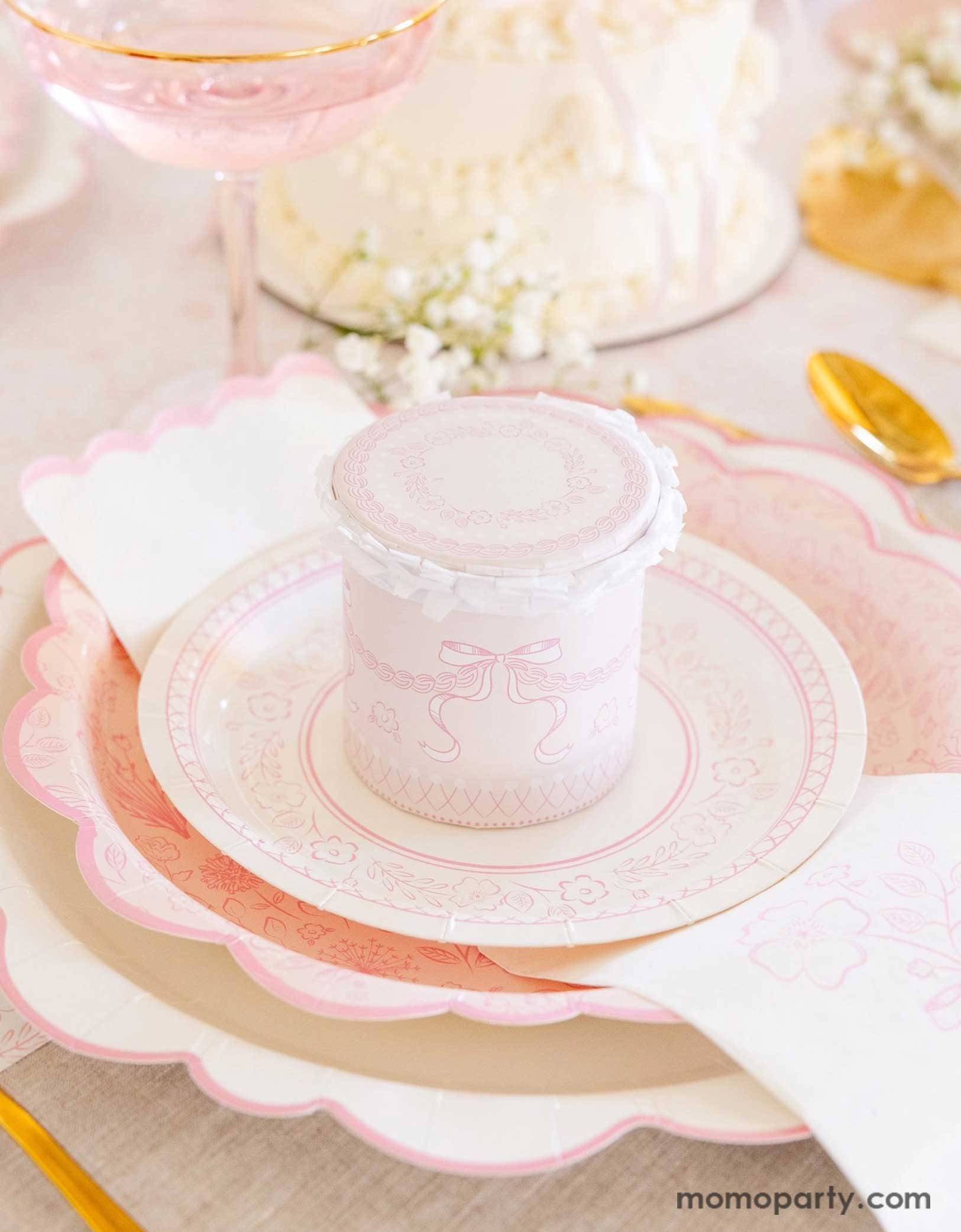 An elegant placeset featuring Momo Party's Pink Pembroke tableware collection including the 12" Pembroke Pink Edge Scallop Plate paired, 9" Pembroke Pink floral Plate, 7" Pembroke Pink Plate, and the Pembroke Pink napkin. With the gold foil utensil set, a pretty floral arrangement, a pink buttercream cake and a pink champagne glass, this table setting is perfect for a spring inspired celebration, be it an Easter celebration or Mother's Day party.