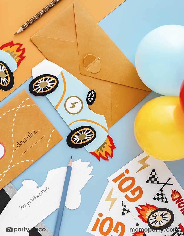 Two sets of Momo Party's race car stickers by Party Deco surrounded by some stationary and some colorful party balloons. The vintage race car shaped invitations and the envelops are adorned with the race car themed stickers, making it a perfect inspo for kid's race car themed birthday DIY invitation ideas.