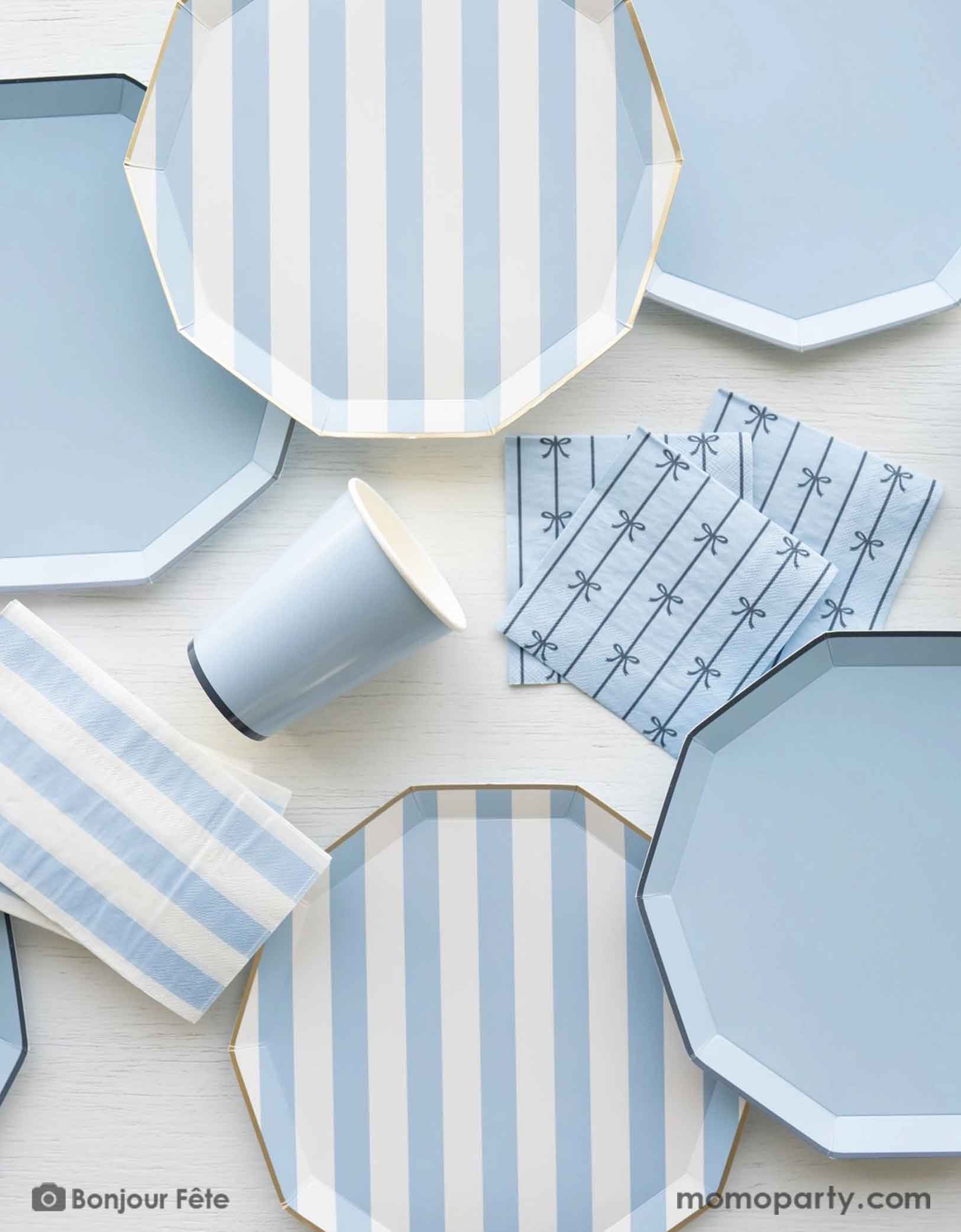 An overhead shot of a party table filled with Momo Party's pastel blue themed party tableware including sky blue cabana striped dinner plates, napkins and pastel blue dinner plates in decagon shape with matching napkins with bows and party cups - a great collection for boy's birthday or a baby boy shower. 