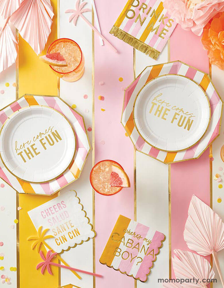 A festive pink and orange summer themed part table featuring Momo Party's here comes the fun party supplies including cheerful plates, napkins in pink and orange stripes, palm tree shaped stirrers, summer bouquets and refreshing summer drinks topped with tropical fruit - a perfect inspo for a fun and bright summer celebration in the sun!