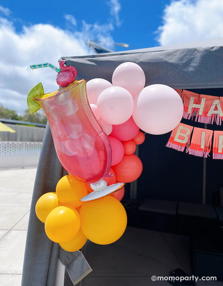 Summer Pool Party by Momo Party. Enjoy a poolside tent adorned with the 'Let's Flamingo Drink Foil Mylar Balloon' and coral, pink, goldenrod, and rose latex balloons. A bright yellow outdoor chair completes the vibrant summer vibe. Perfect for your summer bash! Additionally, decorate with the 'Pink Happy Birthday Fringe Garland' to add a festive touch to your celebration. It's also perfect for your tropical or luau party in the summer.