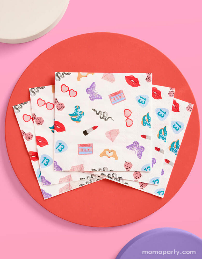 Momo Party's 5" x 5" Taylor Swift Era's Party small napkins Xo, Fetti. Comes in a set of 25 napkins, these napkins have a Taylor Swift inspired motif featuring red lipstick, red lips, butterflies, cowgirl boots, snakes, cassette tapes, guitar picks, heart hand symbols, and heart shaped sunglasses.  They're perfect for the party table celebrating your Swiftie girl's special day. 