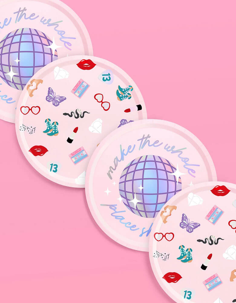 Momo Party's 9" x 9" Taylor Swift Era's Party Paper Plates by Xo, Fetti. Comes in a set of 24 paper plates in two different designs, a disco ball and a Taylor Swift inspired motif featuring red lipstick, red lips, butterflies, cowgirl boots, snakes, cassette tapes, guitar picks, heart hand symbols, and heart shaped sunglasses.  They're perfect for the party table celebrating your Swiftie girl's special day. 