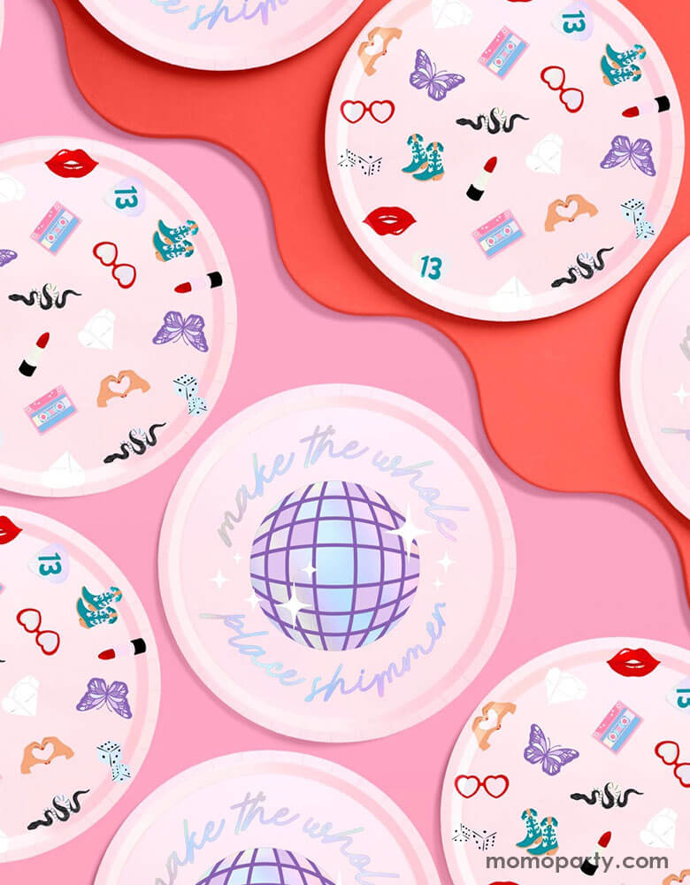 Momo Party's 9" x 9" Taylor Swift Era's Party pink paper plates by Xo, Fetti. Comes in a set of 24 paper plates in two different designs, a disco ball and a Taylor Swift inspired motif featuring red lipstick, red lips, butterflies, cowgirl boots, snakes, cassette tapes, guitar picks, heart hand symbols, and heart shaped sunglasses.  They're perfect for the party table celebrating your Swiftie girl's special day. 