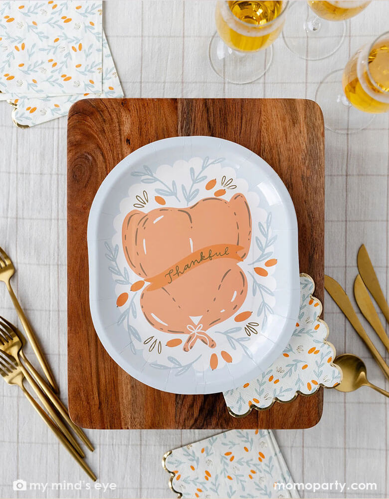 An overhead shot of Momo Party's 10" roasted turkey plate on a chopping board surrounded by tableware, champaign glasses and gingham checkered tablecloth - a perfect setting for a Thanksgiving gathering table this fall.