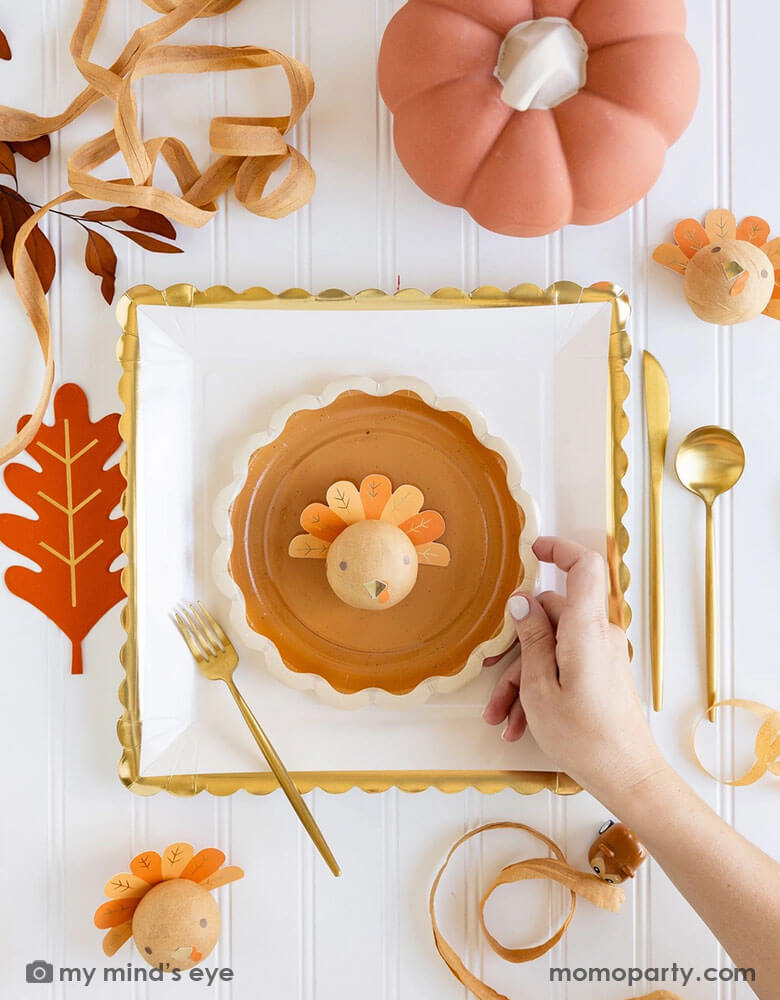 A beautiful and playful Thanksgiving tablescape features Momo Party's Thanksgiving party supplies including fall inspired paper plates, oak leaf shaped napkins and turkey surprise balls. A perfect inspo for a modern Thanksgiving dinner tableset in this harvest season.