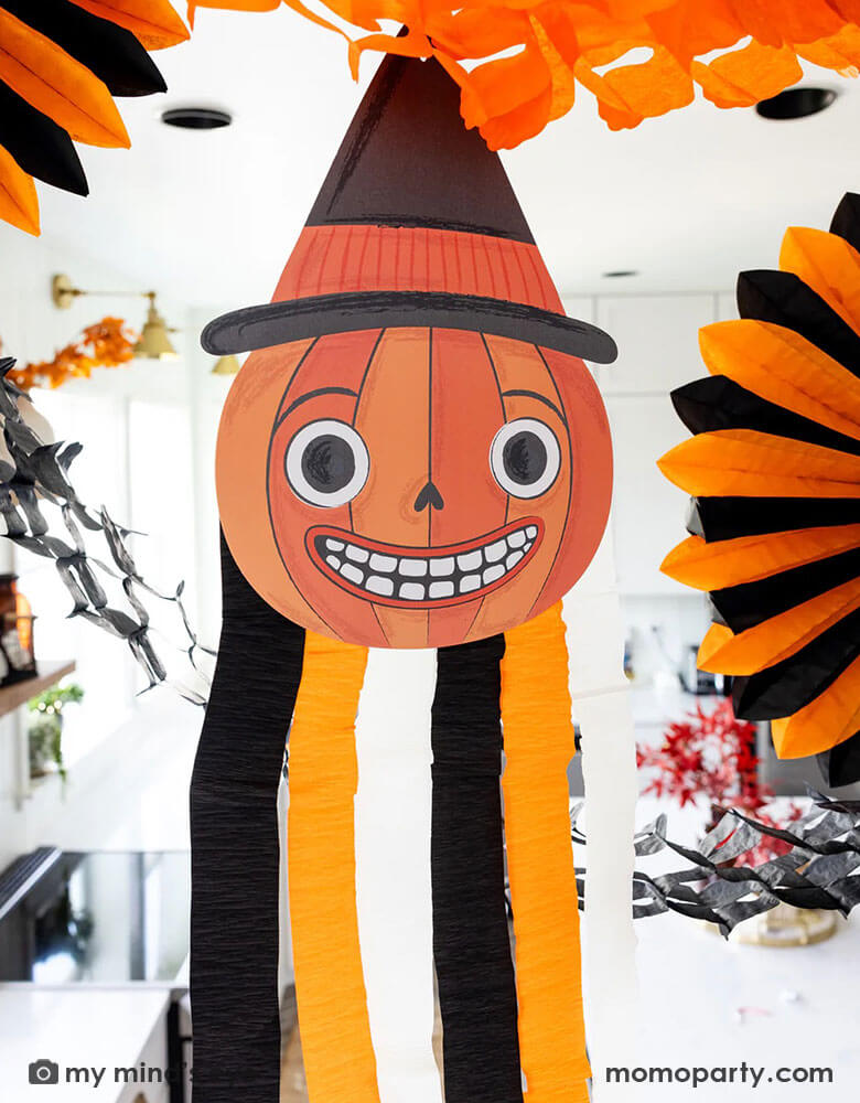 A close-up shot of a modern kitchen that's decorated with vintage inspired Halloween party supplies form Momo Party including the Halloween hanging characters decoration of a pumpkin, which around it hung the oversized orange and black paper fans and tissue decorations. Making this a eerie yet fun decoration that sets a festive scene for your Halloween celebration this spooky season.